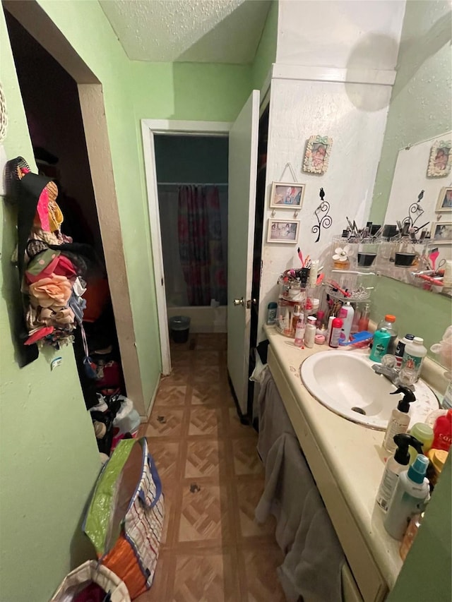 bathroom with shower / bath combo with shower curtain, vanity, and a textured ceiling