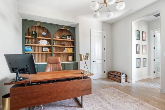 office space with light hardwood / wood-style flooring, built in features, and an inviting chandelier