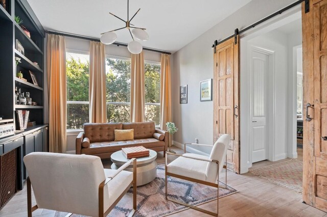 living area featuring light wood-type flooring, a barn door, and an inviting chandelier