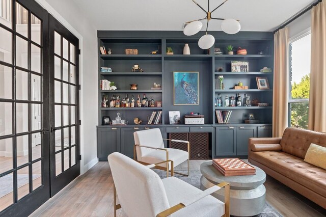 sitting room with built in features, light hardwood / wood-style flooring, and french doors