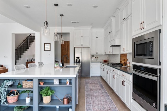 kitchen featuring white cabinetry, a large island, sink, a breakfast bar area, and appliances with stainless steel finishes