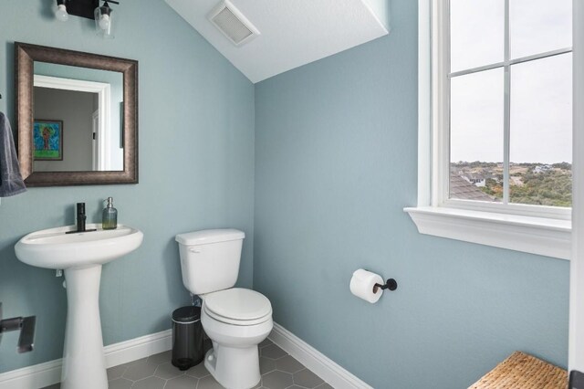 bathroom with tile patterned floors, lofted ceiling, and toilet