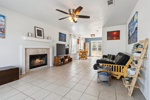 living room with ceiling fan, light tile patterned flooring, a fireplace, and french doors