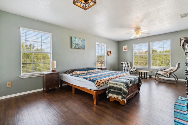 bedroom with a textured ceiling, ceiling fan, and dark wood-type flooring