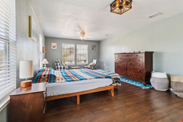 bedroom with ceiling fan, hardwood / wood-style floors, and a textured ceiling