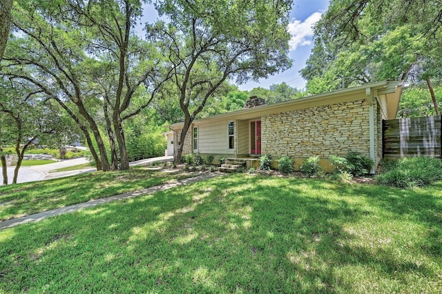 single story home featuring stone siding, a chimney, and a front lawn