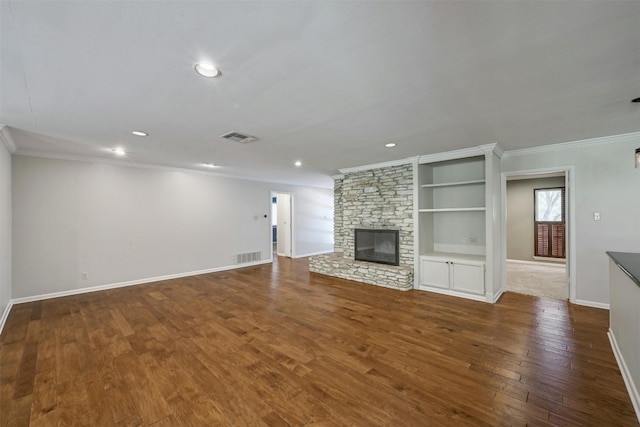 unfurnished living room with hardwood / wood-style flooring, built in shelves, a stone fireplace, and ornamental molding