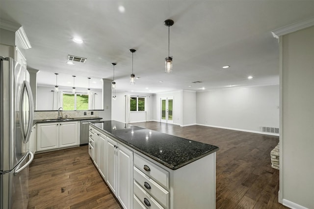 kitchen featuring pendant lighting, sink, tasteful backsplash, white cabinetry, and stainless steel appliances