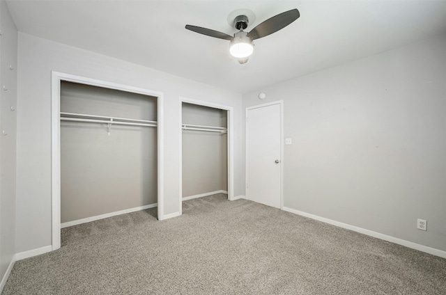 unfurnished bedroom featuring carpet flooring, ceiling fan, and multiple closets