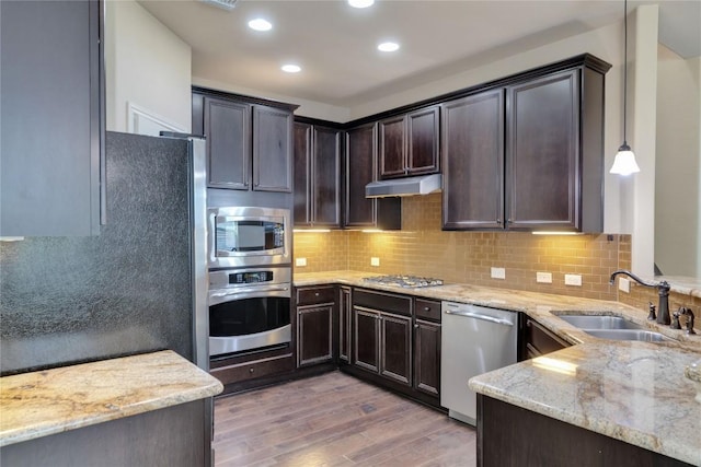 kitchen featuring sink, stainless steel appliances, light stone counters, dark hardwood / wood-style floors, and decorative light fixtures