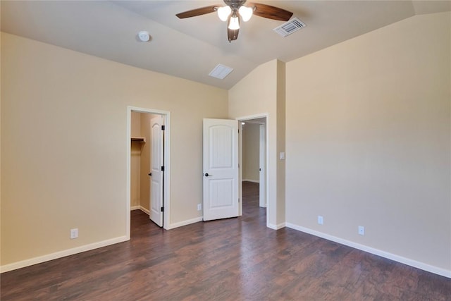 unfurnished bedroom featuring lofted ceiling, a walk in closet, ceiling fan, dark hardwood / wood-style floors, and a closet