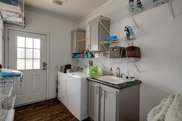 clothes washing area with cabinets, crown molding, sink, washing machine and clothes dryer, and dark hardwood / wood-style floors