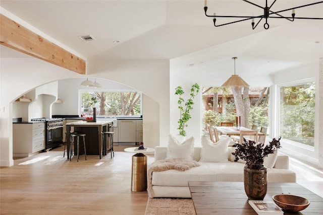 interior space featuring vaulted ceiling, light hardwood / wood-style flooring, a wealth of natural light, and an inviting chandelier