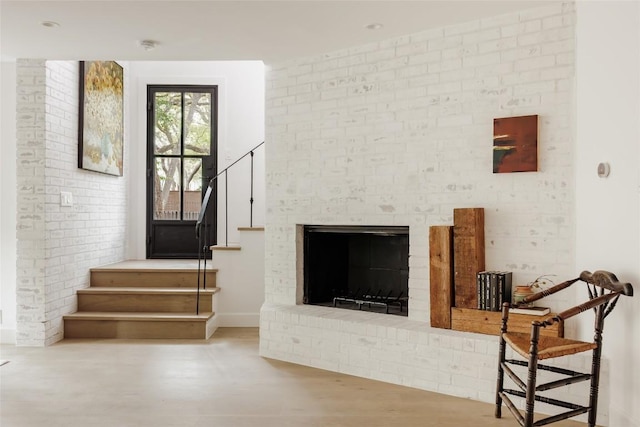 unfurnished living room with a fireplace, light hardwood / wood-style flooring, and brick wall