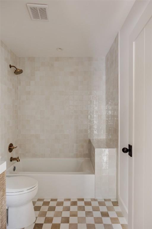 bathroom featuring toilet and tiled shower / bath