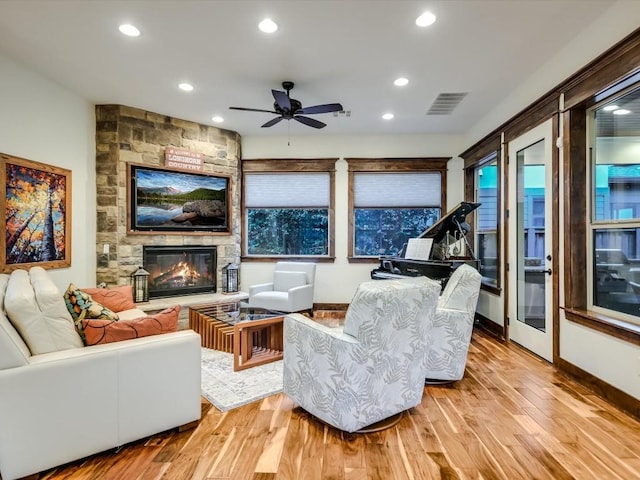 living room featuring a fireplace, light hardwood / wood-style floors, and ceiling fan