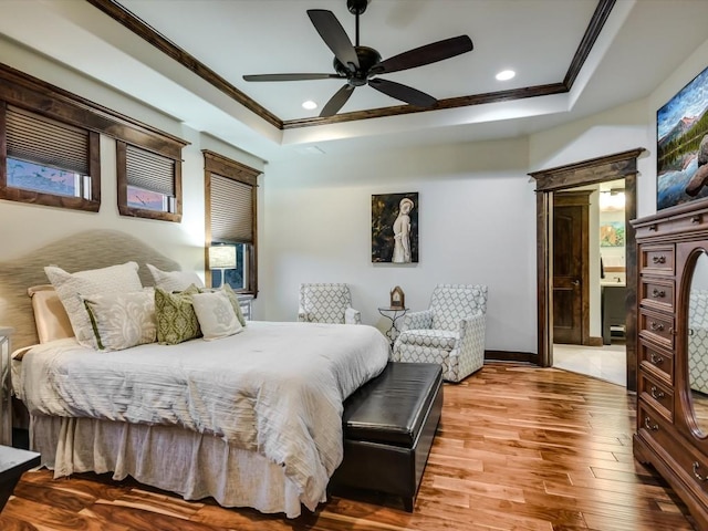 bedroom with wood-type flooring, a raised ceiling, ceiling fan, and ornamental molding