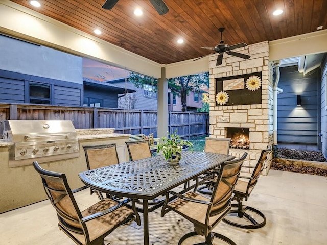 view of patio with area for grilling, ceiling fan, and an outdoor stone fireplace