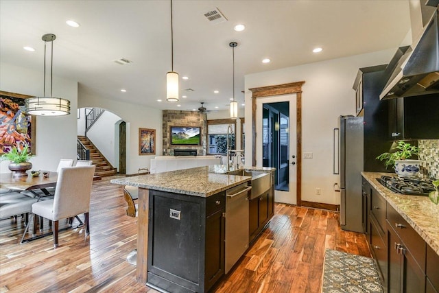 5608 Clay Ave Unit A, Austin, TX 78756 - kitchen featuring under cabinet range hood, appliances with stainless steel finishes, open floor plan, a fireplace, and wood finished floors