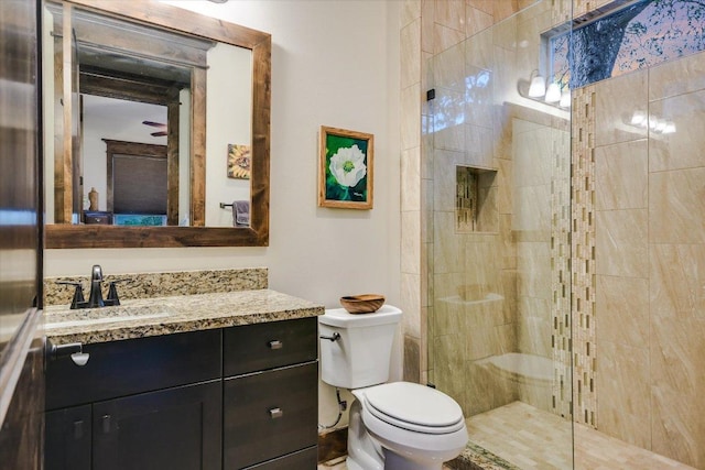 bathroom featuring toilet, a tile shower, and vanity