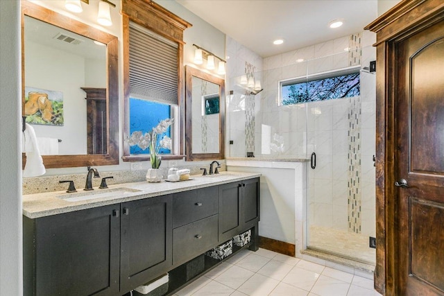 bathroom featuring double vanity, a stall shower, a sink, and visible vents