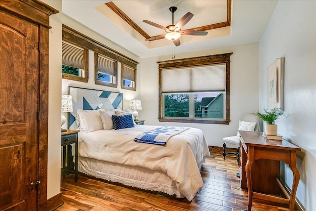 bedroom featuring a ceiling fan, ornamental molding, a raised ceiling, and hardwood / wood-style floors