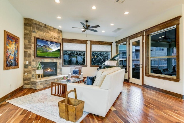 living area featuring recessed lighting, visible vents, wood finished floors, and a stone fireplace