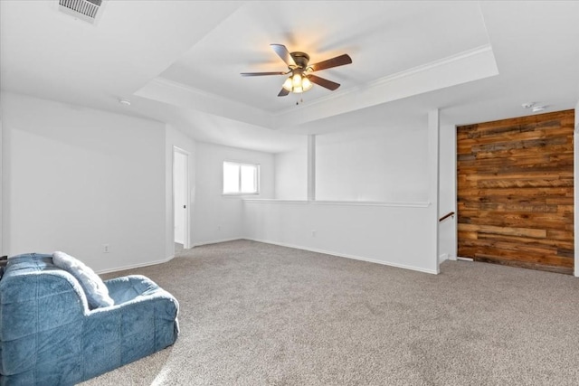 living area featuring a raised ceiling, ceiling fan, and light colored carpet