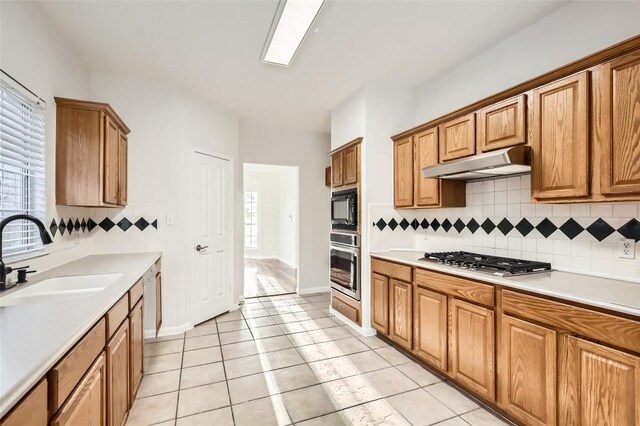 kitchen featuring decorative backsplash, sink, a healthy amount of sunlight, stainless steel appliances, and light tile patterned floors