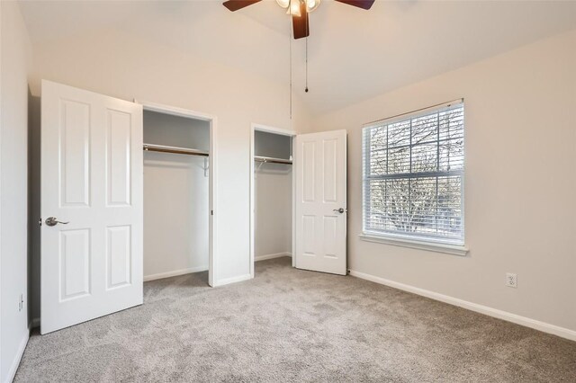 unfurnished bedroom featuring vaulted ceiling, ceiling fan, two closets, and light colored carpet