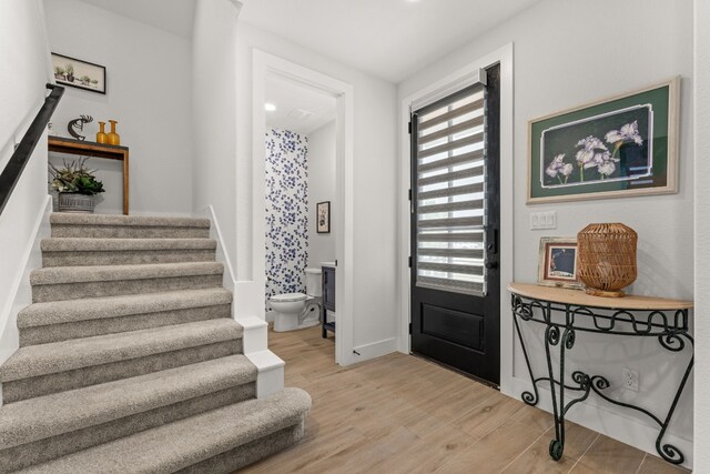 foyer entrance with light wood-type flooring, stairs, and baseboards