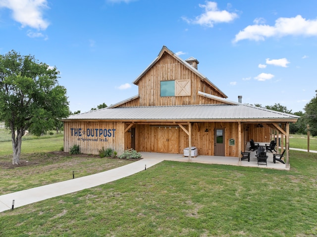 view of front facade featuring a barn, metal roof, a patio, and a front yard