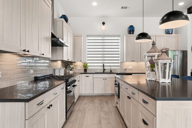 kitchen featuring dark countertops, high end stove, visible vents, and a sink