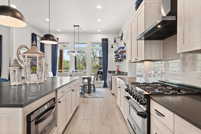 kitchen with dark countertops, wall chimney exhaust hood, high end stainless steel range oven, and decorative backsplash