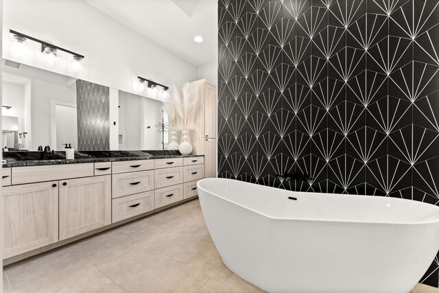 bathroom with visible vents, a soaking tub, tile patterned floors, vanity, and tile walls