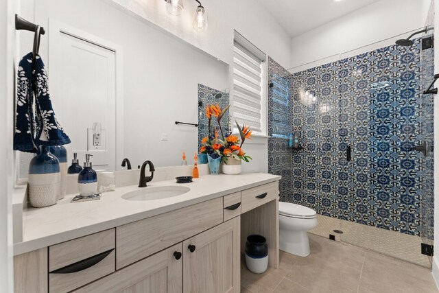 full bathroom with tiled shower, vanity, toilet, and tile patterned floors