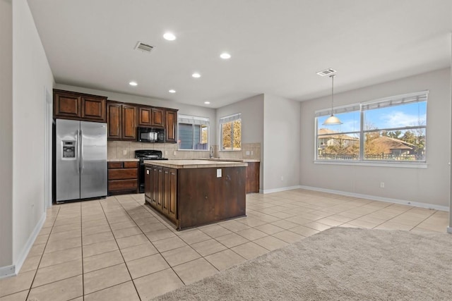 kitchen with pendant lighting, stainless steel refrigerator with ice dispenser, light tile patterned floors, dark brown cabinetry, and range with gas cooktop