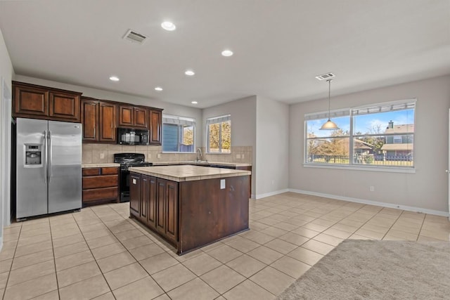 kitchen with pendant lighting, black appliances, sink, light tile patterned floors, and tasteful backsplash