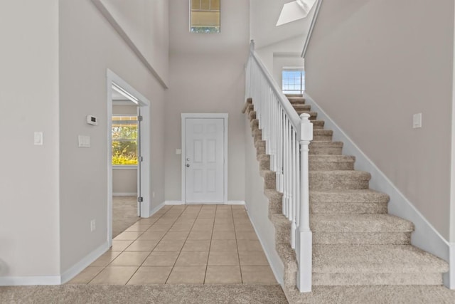 carpeted foyer entrance featuring a skylight and a high ceiling