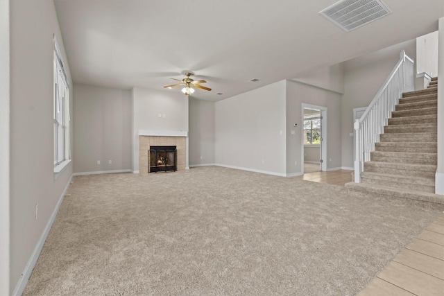 unfurnished living room with ceiling fan, light colored carpet, and a fireplace