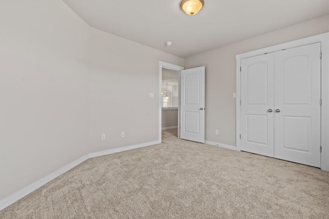 unfurnished bedroom with light carpet and a closet