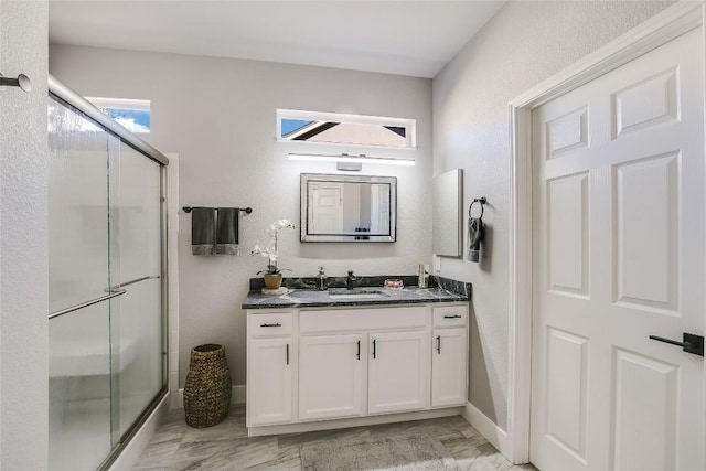 bathroom featuring a shower with door and vanity