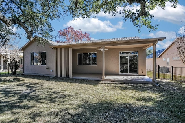 rear view of house with ceiling fan, a patio area, and a lawn