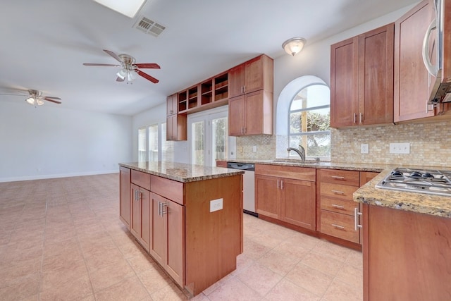 kitchen with light stone counters, sink, a kitchen island, and appliances with stainless steel finishes