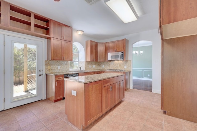 kitchen featuring decorative backsplash, light stone counters, dishwasher, and a kitchen island