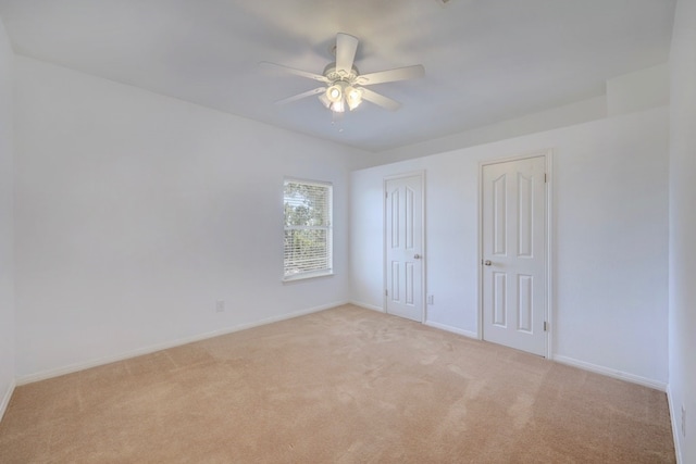 unfurnished bedroom with ceiling fan, light carpet, and two closets