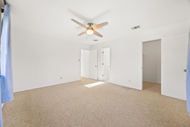 unfurnished bedroom featuring ceiling fan, light colored carpet, a walk in closet, and a closet