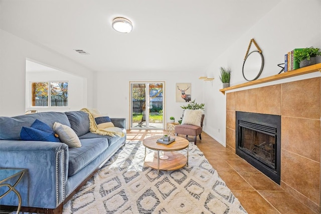 living room featuring a healthy amount of sunlight, light tile patterned floors, and a tile fireplace