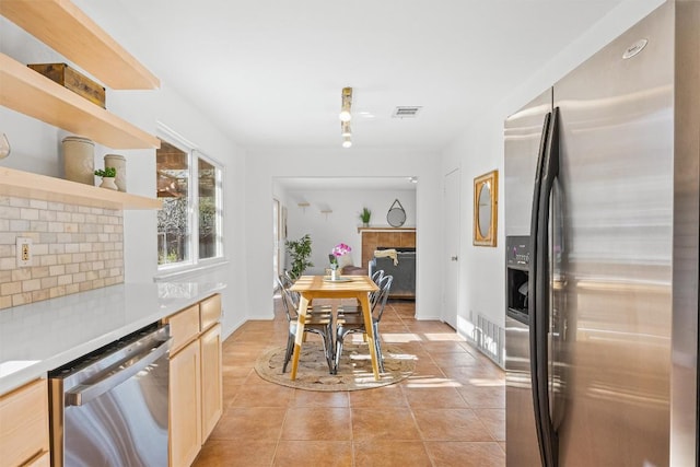 kitchen with light brown cabinets, light tile patterned flooring, and stainless steel appliances