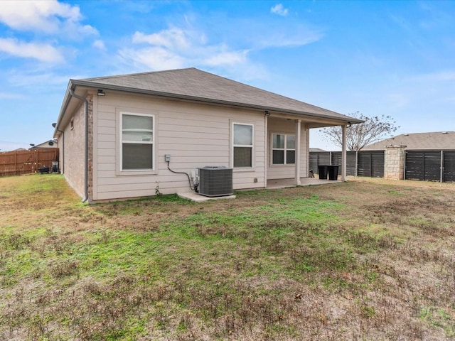 rear view of property with cooling unit and a yard